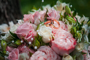 A pair of gold wedding rings on a bride's bouquet with colorful flowers