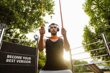 Young muscular man doing workout with fitness rubber bands outdoors