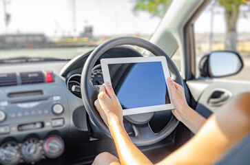 Woman holding tablet computer sitting in the car.