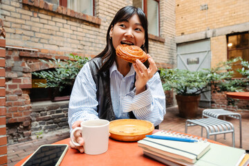 Asian girl eating cinnabon bun while sitting in cafe