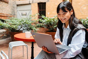 Young asian girl using laptop computer while sitting in cafe