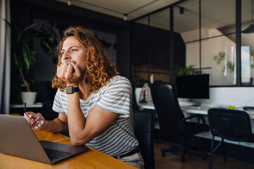 Young manager working on laptop while sitting at table in office