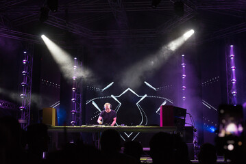 Dj playing techno music on the concert stage at summer night