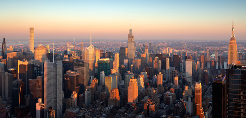 New York City aerial view of midtown Manhattan skyscrapers in warm light of sunset. The elevated view includes landmarks and some of the newest supertall buildings