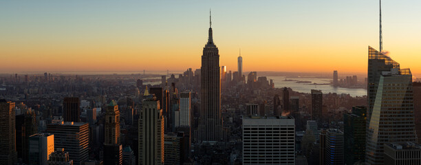 New York City aerial panoramic view of Midtown Manhattan skyscrapers at sunset. The view includes Brooklyn (left), Lower Manhattan and New York Harbor (in the distance) and the Hudson River (right) - obrazy, fototapety, plakaty