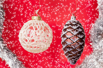 Two christmas tree ornaments on a red background in a silver tinsel frame and shining stars....