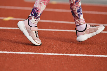 Girl in the pink sneakers runs in the stadium