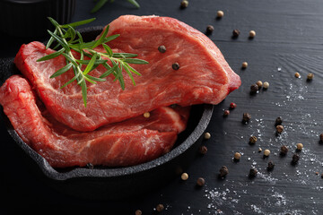 Fresh meat with ingredients for cooking on dark table