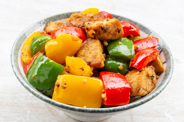 Food healthy stir fried chicken add sweet peppers in bowl on wood table.
