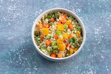 Healthy food cauliflower fried rice has vegetable in white bowl on blue wood table.