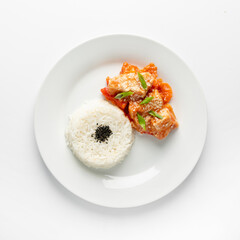 A close-up of Asian-style rice with chicken in sour sweet sauce on a white plate, isolated on white top view.