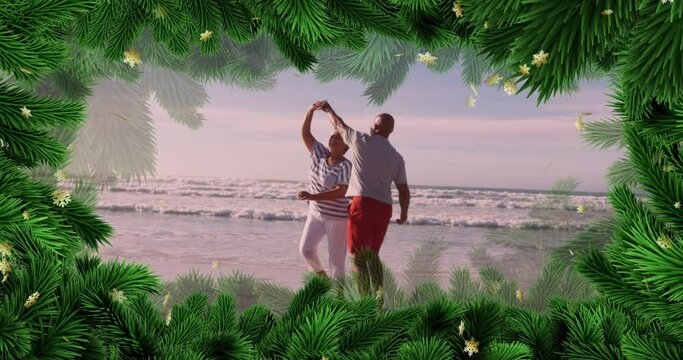Animation of fir tree frame over happy diverse senior couple danging on beach