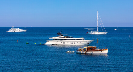 Panoramic view of harbor and yachts with French riviera shore in background seen from Azure Cost of Mediterranean Sea in Antibes resort town in France