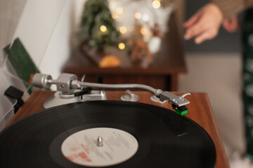 turntable with record playing music on Christmas Day holiday season with yellow bokeh lights. Cozy vintage background.