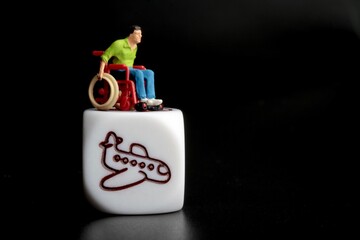 miniature figurine of a disabled man on a wheelchair with an airplane symbol