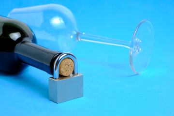 Glass and bottle wine with lock on neck on blue background.Concept ban on drinking, prohibition.