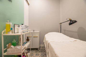 A booth with a stretcher, black articulated lamp in a beauty salon
