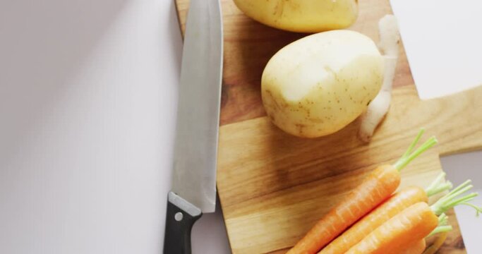 Overhead video of knife and vegetables on chopping board, with vegetable waste in bin for composting