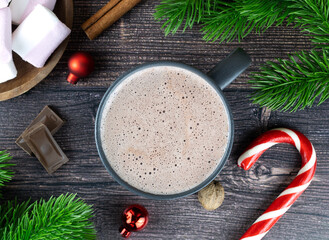 Delicious hot winter cocoa drink with chocolate pieces, marshmallows, spruce branches and Christmas balls. Top view.