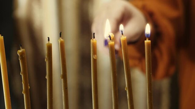 A woman's hand lights candles on the last day of Hanukkah from the shamash candle