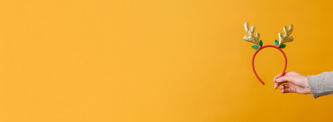 New Year's headdress: deer horns in a female hand on a yellow background.BannerCopy space