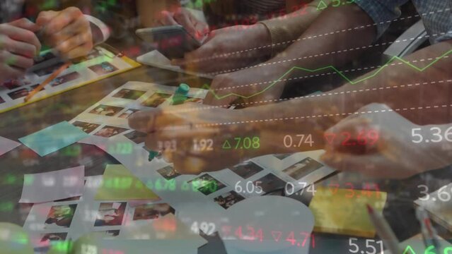 Animation of stock market data processing over mid section of graphic designers discussing
