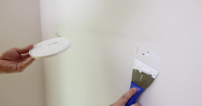 Repairman closing up holes in wall with putty and spatula closeup 4k movie slow motion