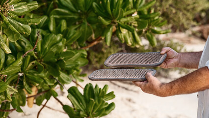 a faceless man holds sadhu boards with sharp nails on the seashore with white sand, the concept of yoga practice, meditation, concentration. close-up