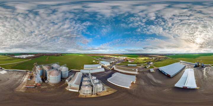 full seamless 360 hdri panorama view among farming field on rows of agro silos granary elevator with seeds cleaning line on agro-processing manufacturing plant in equirectangular spherical projection