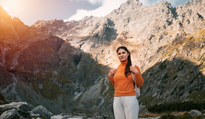 Naklejka na ściany i meble A beautiful brunette woman is hiking in the mountains of Europe. Young girl relaxing in the Tatra Mountains. Concept of a healthy active life outdoor