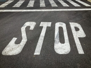 Señal de STOP en una calle asfaltada con un paso de peatones (paso zebra) delante - obrazy, fototapety, plakaty