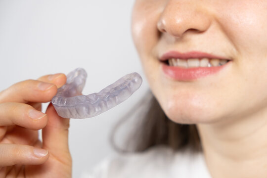 A woman holds dental mouthguard, splint for the treatment of dysfunction of the temporomandibular joints, bruxism, malocclusion, to relax the muscles of the jaw.