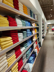 Piles of multicolored towels on the shelves in a shop.