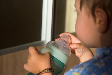 Toddler holding a baby bottle with a drink close-up