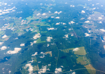 Aerial view from airplane window above green ground. View from the airplane window with beautiful clouds at sunrise © Dmitrii Potashkin