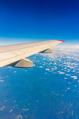 Fototapeta premium View from the airplane window at a beautiful cloudy sky and the airplane wing