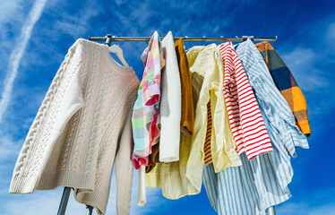  Low angle view at colourful clothes hanging on rail against blue sky.