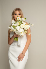 Vertical confident charming romantic blond female bride in white elegant dress covered by bouquet of white field flowers