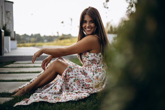 Attractive woman in summer dress sitting on ground