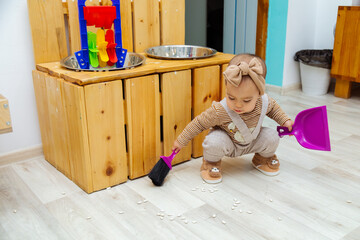 Toddler cleaning up spilled beans at montessori Practical Life Area