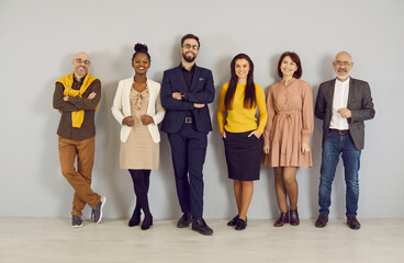 Fototapeta premium Group portrait of smiling diverse businesspeople pose on grey wall background in office. Happy multiracial colleagues or coworkers show unity at workplace. Employment or recruitment concept.