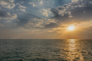 Beautiful sunset over calm sea, majestic clouds in the sky and beautiful rays of sun shining through the clouds