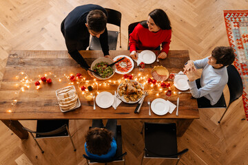 Multi generation family eating food together at christmas dinner at home