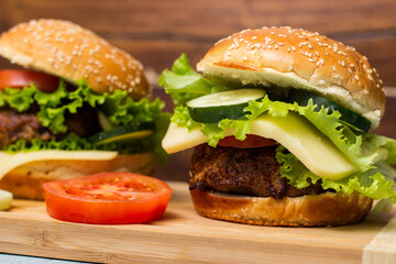 Burgers with beef meat, cheese and lettuce, served on cutting board