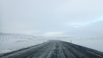 A grey road in a snowy white landscape.