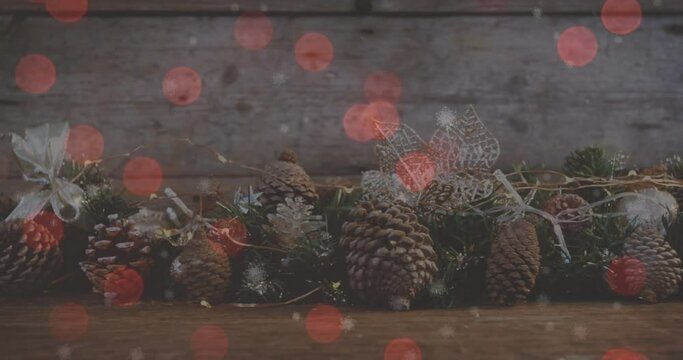 Animation of red spots of light over christmas decoration with pine cones