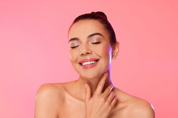 Portrait of young woman with beautiful makeup on light pink background
