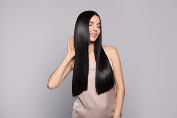 Portrait of beautiful young woman with healthy strong hair on light grey background