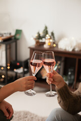 Drinking sparkling rose wine or champagne at home decorated for winter holidays. Christmas season festive drinks.