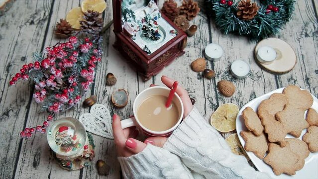 Christmas Close up hands of woman holding cup with hot tea at decorated table. Top view of Christmas decorations. vibe and atmosphere of holidays. Cozy copy space background. New Year winter vacation